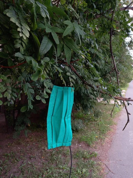 Saint Petersburg, Russia, August 14, 2020. Used disposable mask hanging on the tree. Garbage problem due to the use of medical masks in the COVID-19 pandemic