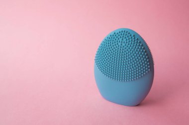Yüzünü yıkamak için silikon fırça. Pembe arka planda mavi yüz temizleme fırçası. Güzellik ve cilt bakımı. Yüz gerdirme için fırça, yaşlanma önleyici kırışıklıklar ve masaj. Kopyalama alanı ile resim
