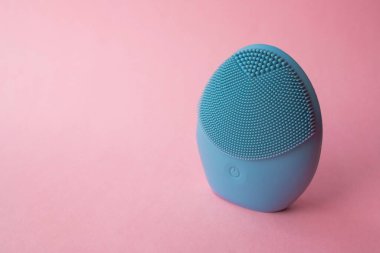 Yüzünü yıkamak için silikon fırça. Pembe arka planda mavi yüz temizleme fırçası. Güzellik ve cilt bakımı. Yüz gerdirme için fırça, yaşlanma önleyici kırışıklıklar ve masaj. Kopyalama alanı ile resim