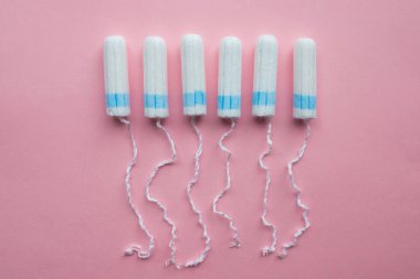 Tek kullanımlık tamponlar pembe arka planda yatıyordu. Kadın Sağlığı.