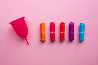 Adet bardağı ve tampon. Tekrar kullanılabilir adet bardağı, tek kullanımlık tamponlara alternatif. Pembe arka planda düz yatıyordu. Sıfır atık. Çevreye önem vermek. Kadın Sağlığı.