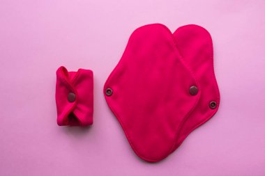 Yeniden Kullanılabilir Kumaş Hijyenik Adet Pedleri. Pembe arka planda düz bir manzara vardı. Sıfır atık. Çevreye önem vermek. Kadın Sağlığı. Bilinçli tüketim. Tek kullanımlık pedlere alternatif.
