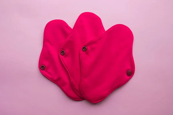 Yeniden Kullanılabilir Kumaş Hijyenik Adet Pedleri. Pembe arka planda düz bir manzara vardı. Sıfır atık. Çevreye önem vermek. Kadın Sağlığı. Bilinçli tüketim. Tek kullanımlık pedlere alternatif.