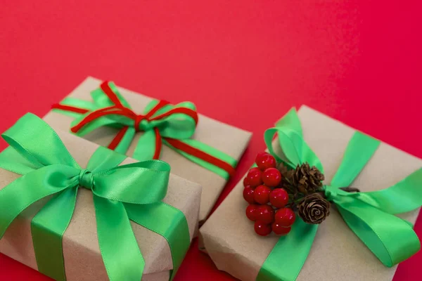 用手工纸包好 用绿色和红色缎带装饰的礼物铺在红色的背景上 具有复制空间和场浅层深度的顶视图图像 — 图库照片