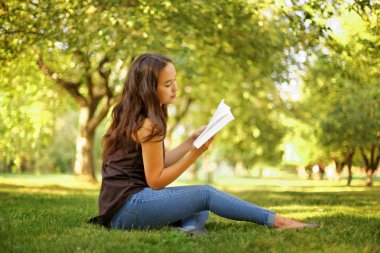 Kazak güzel kız, yaz parkında kitap okuyor.