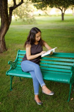 Kazak güzel kız, yaz parkında kitap okuyor.
