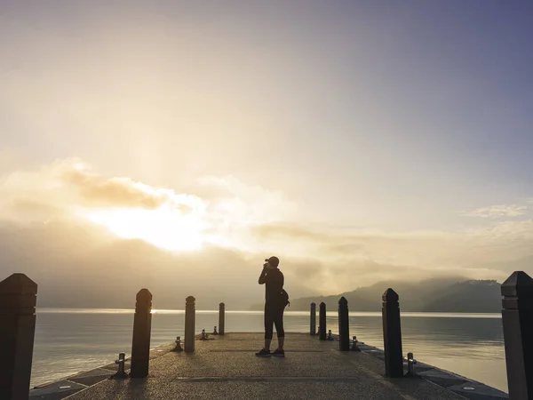 Viajero tomar una foto en muelle Lago al aire libre amanecer Naturaleza paisaje — Foto de Stock