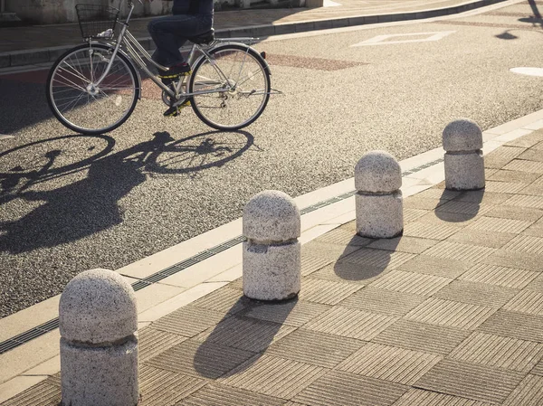 走道上的波拉德，人们在街上骑自行车 — 图库照片