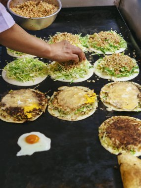 Japon sokak yemekleri Okonomiyaki sıcak tabakta, aşçı pişirdi. 