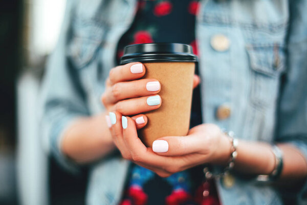 Female hand with paper cup of coffee take away.