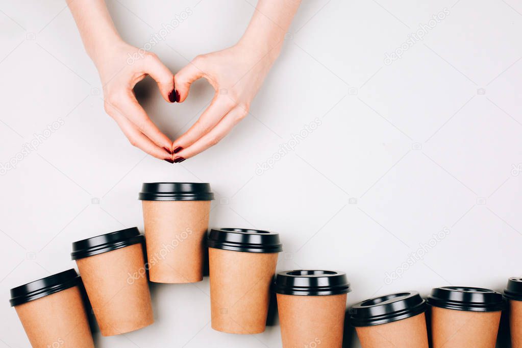 Loving coffee concept. Two hands making heart between many paper cups of coffee to go
