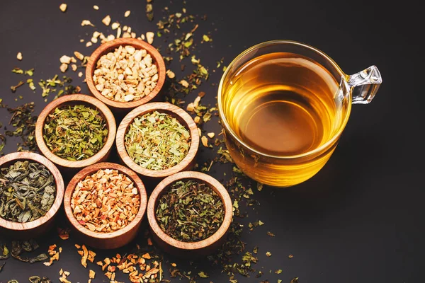 siyah arka plan üzerine küçük kase kuru çay ürün yelpazesine. Yeşil ve siyah çay, nane, melissa, zencefilli, elma, ıhlamur ağacı ve diğer bileşenleri 