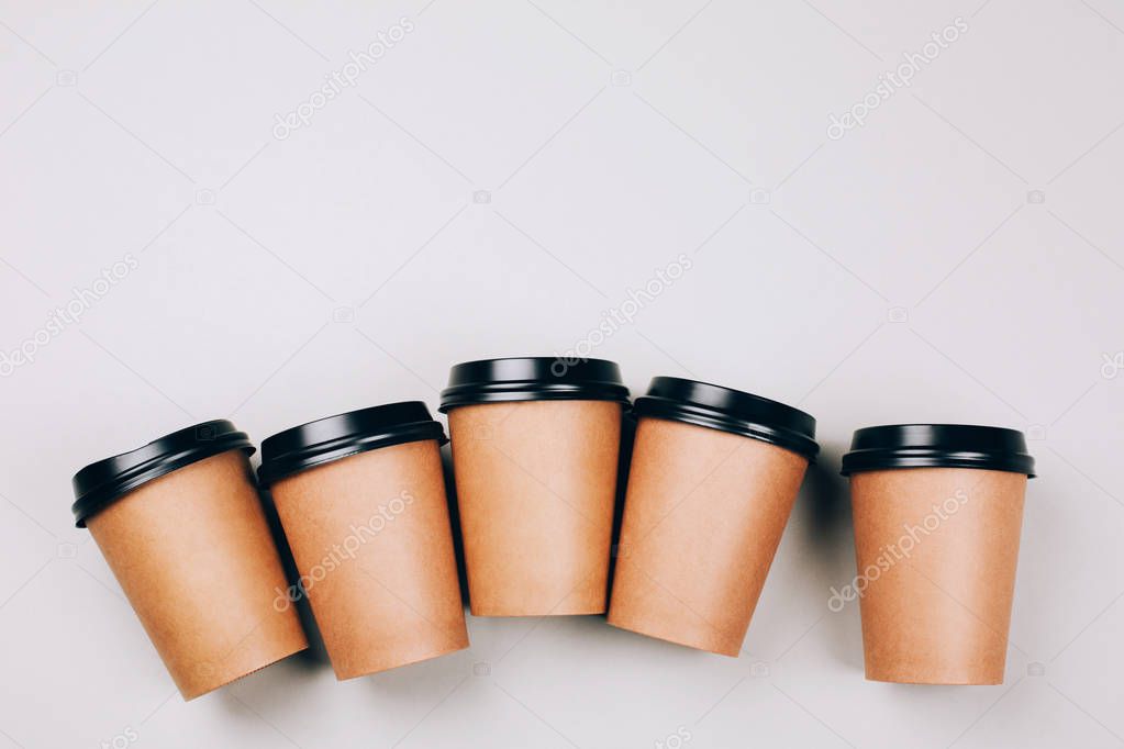 many brown craft cups of coffee to go on grey background, flat lay 