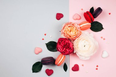 Kompozisyon macarons ve gri ve pembe renklerde çiçek. Düz yatıyordu. Metniniz için yer.