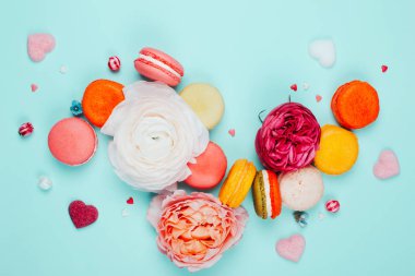 Kompozisyon macarons ve gri ve pembe renklerde çiçek. Düz yatıyordu. Metniniz için yer.