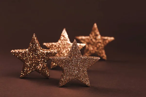 Estrelas cintilantes douradas sobre fundo marrom — Fotografia de Stock