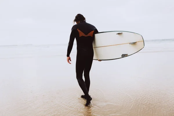 Серфер з дошкою для серфінгу йде в океан — стокове фото