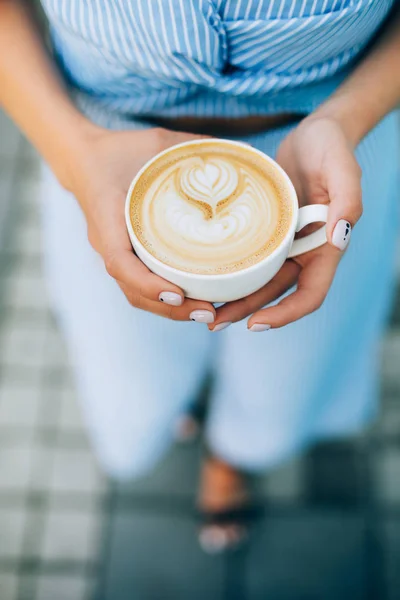 Mulher segurando xícara de cappuccino com arte latte — Fotografia de Stock