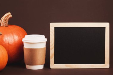 Baharatlar ve kabak ile götürmek için kahve. Geleneksel sonbahar baharatlı latte kavramı. Üzerinde kahverengi kahve sahibi logosunu yerleştirin. Siyah tebeşir ahşap çerçeve ile metin yerleştirmek için masam.