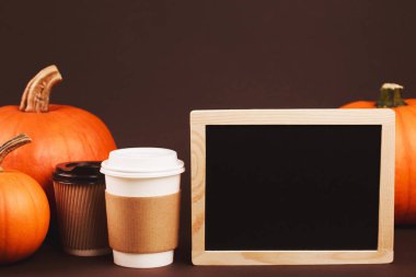 Baharatlar ve kabak ile götürmek için kahve. Geleneksel sonbahar baharatlı latte kavramı. Üzerinde kahverengi kahve sahibi logosunu yerleştirin. Siyah tebeşir ahşap çerçeve ile metin yerleştirmek için masam.