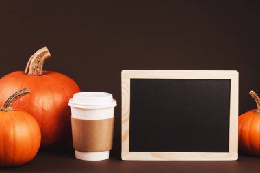 Baharatlar ve kabak ile götürmek için kahve. Geleneksel sonbahar baharatlı latte kavramı. Üzerinde kahverengi kahve sahibi logosunu yerleştirin. Siyah tebeşir ahşap çerçeve ile metin yerleştirmek için masam.