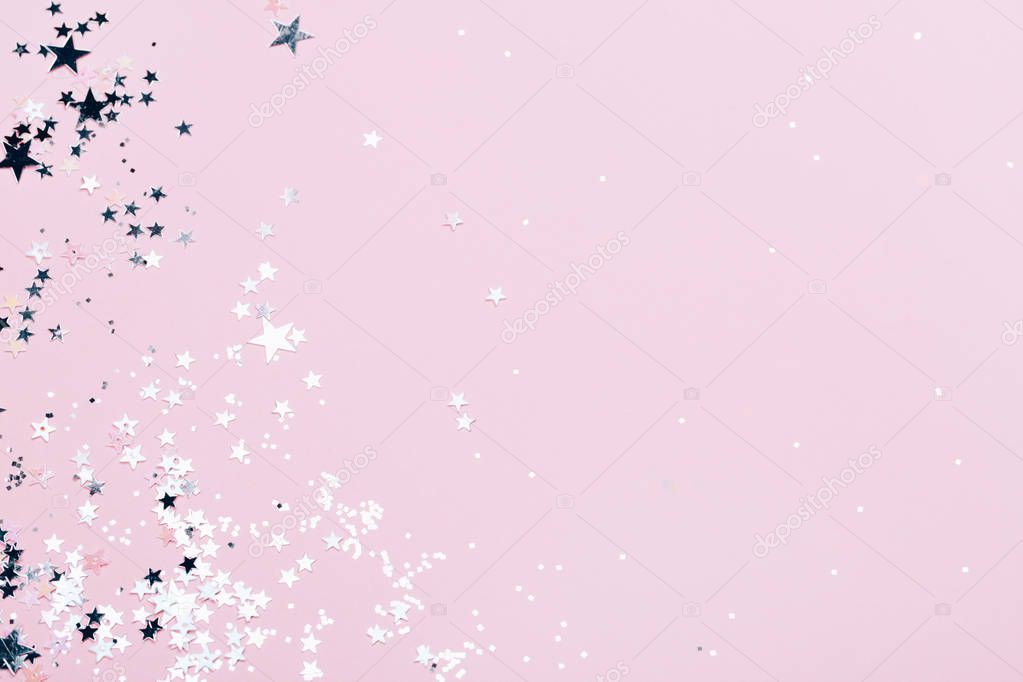 Silver sparkles, stars and glitters on pink background. Festive concept.