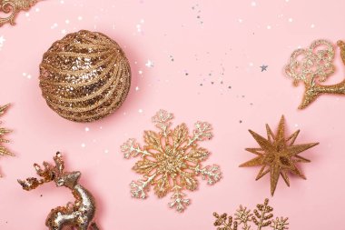 Altın güzel parlak Noel Dekorotif oyuncakları pastel pembe bir arka plan üzerinde. Düz yatıyordu. Festival kavramı.