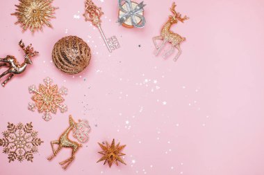 Altın güzel parlak Noel Dekorotif oyuncakları pastel pembe bir arka plan üzerinde.
