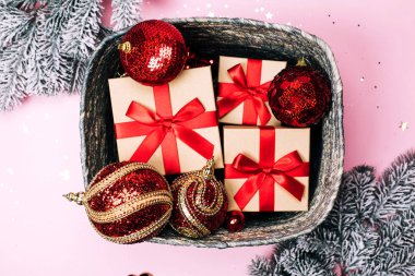 Hediyeler ve baubles ile kutu ve köknar-ağaç pembe pastel arka plan üzerinde kar.