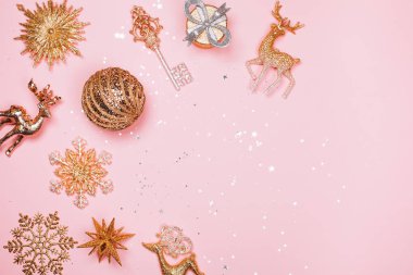 Altın güzel parlak Noel Dekorotif oyuncakları pastel pembe bir arka plan üzerinde.