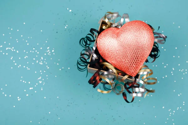 Living Coral heart in opened present box with festive ribbons on sparkling background