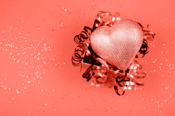 Silver heart in opened present box with festive ribbons on sparkling background