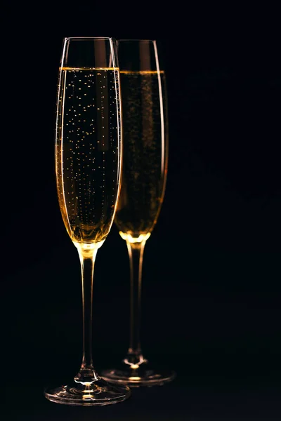 Two glasses of champagne full size on black elegant background. Celebration concept.
