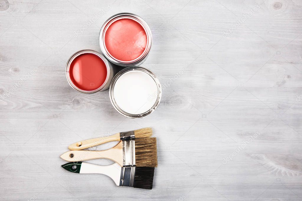 House renovation, paint cans and colored brushes on white wooden background. Living Coral Color of the year 2019.