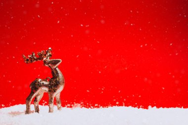Altın Christmas dekoratif geyik kar kırmızı zemin üzerine duruyor. Festival kavramı. Metin için yer.
