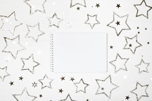 Cuaderno blanco sobre fondo de madera pastel con estrellas de plata . —  Fotos de Stock