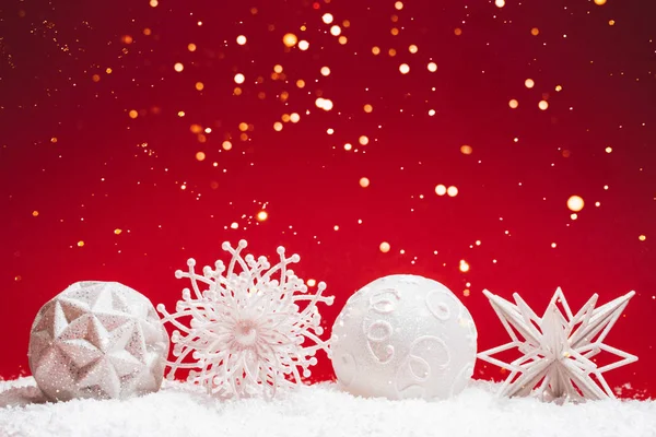 Четыре рождественские декоративные игрушки на красном фоне со снегом . — стоковое фото