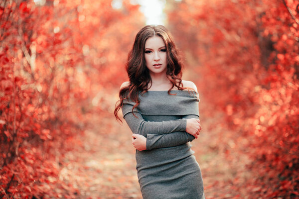 Young sexy woman with long hair in grey dress, in Coral forest. Color of the year 2019. Main trend natural and authentic concept.