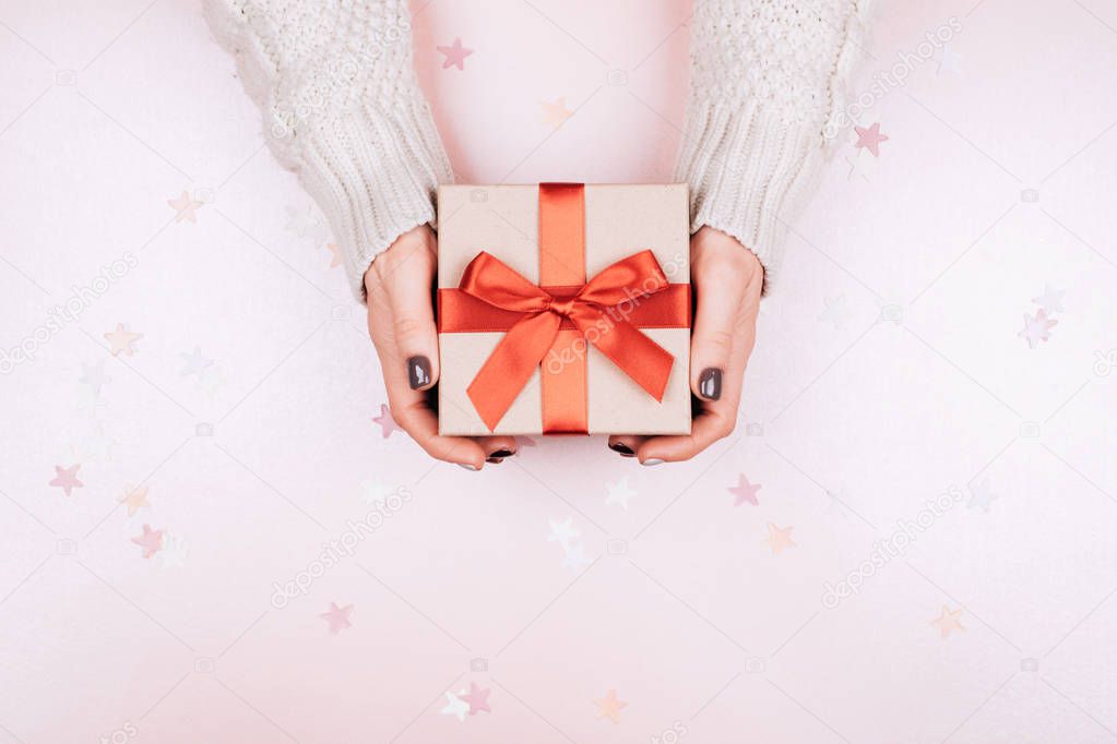 Gift box with bow in woman's hands. Coral - Color of 2019.