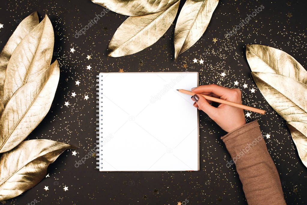 Goal list for New Year. cropped shot of woman writing in notebook with blank page on dark table