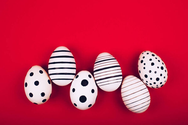 Different graphic hand-painted eggs on bright red background.