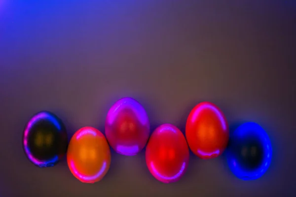 Creative photo of colorful eggs in neon lights on grey background. — Stock Photo, Image
