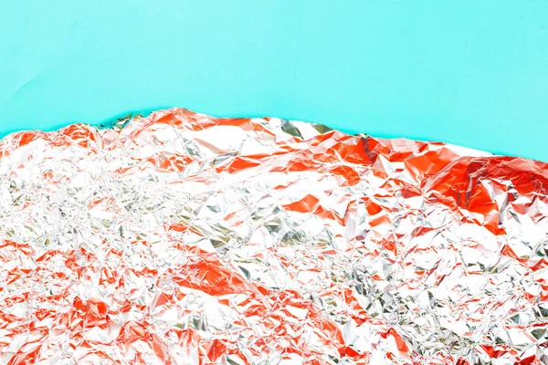 ティールの背景にサンゴの色とくしゃくしゃの箔で作られた抽象的な背景. — ストック写真