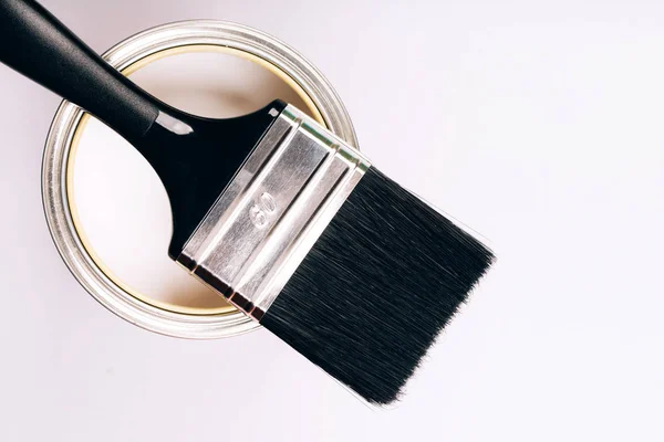 Pinsel mit schwarzem Griff auf offener Dose weißer Farbe auf grauem Hintergrund. — Stockfoto
