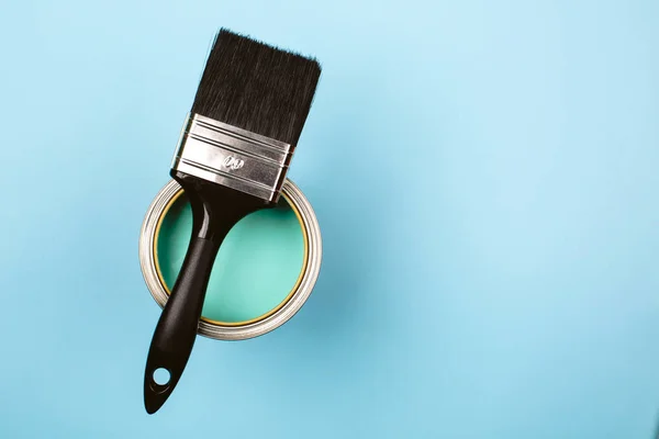 Cepillo en lata abierta de pintura verde azulado sobre fondo pastel azul . —  Fotos de Stock