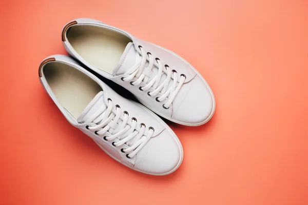 Toes of white trendy sneakers on bright orange background. — Stock Photo, Image
