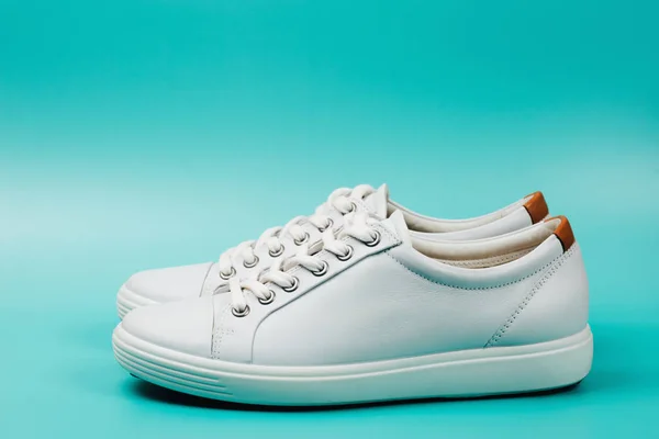 Side view of white trendy sneakers on turquoise background. — Stock Photo, Image