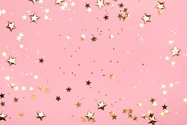 Estrelas douradas brilham sobre fundo rosa . — Fotografia de Stock