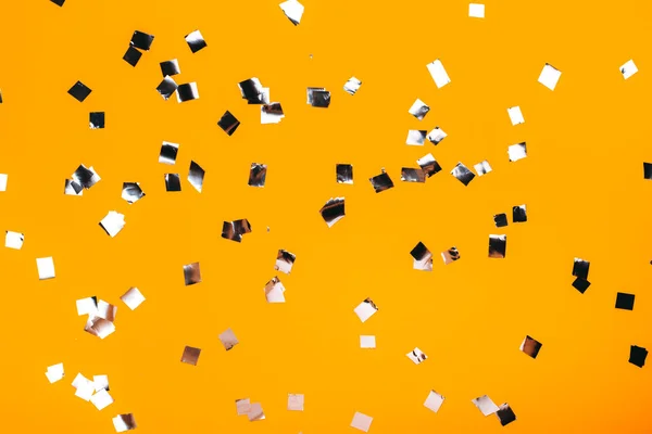 Caída de confeti plateado sobre fondo amarillo —  Fotos de Stock