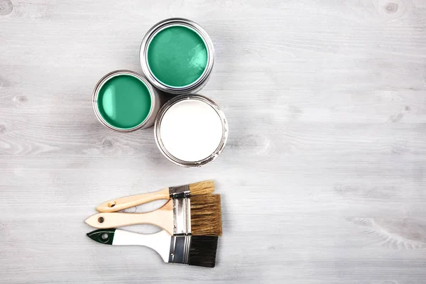 Boîtes de peinture vertes et pinceaux colorés sur fond blanc — Photo